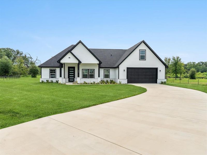 Modern farmhouse featuring a front lawn and a garage