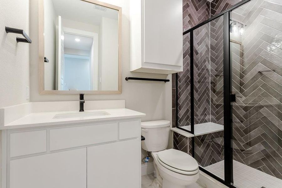 Bathroom with vanity, toilet, and a shower with door