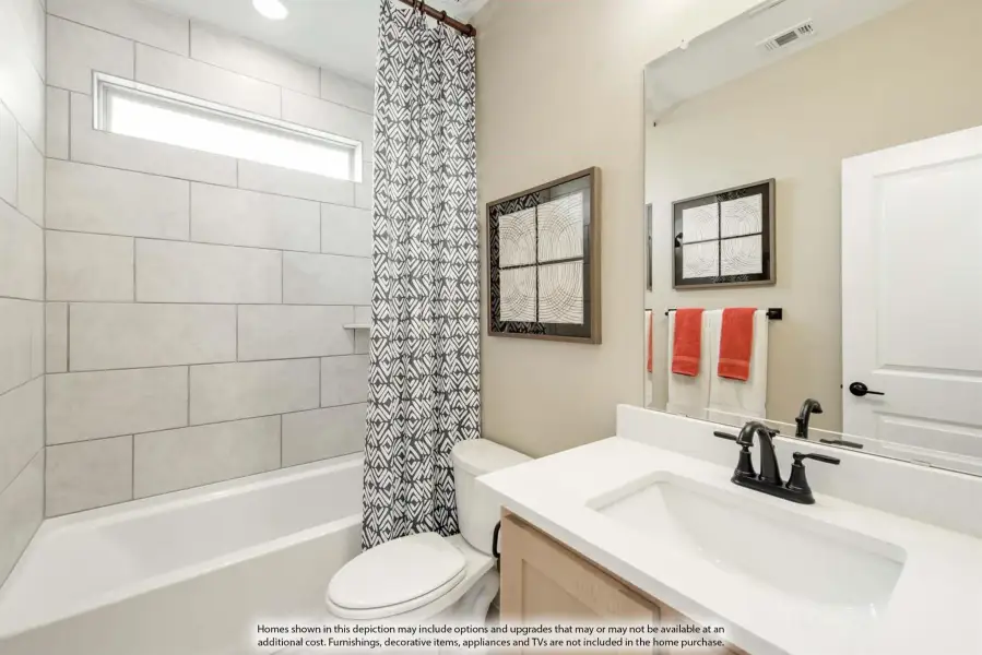 Bathroom with tiled tub-shower combo, patterned curtain, white countertop vanity, and dark fixtures