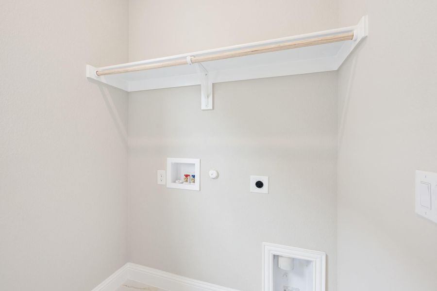 Laundry room with upper shelf, hanging rod, washer hookups, and dryer vent connection on white walls
