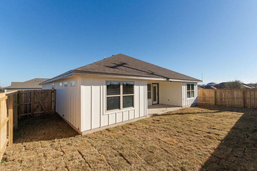 Rear view of property featuring a patio, a fenced backyard, a gate, and roof with shingles