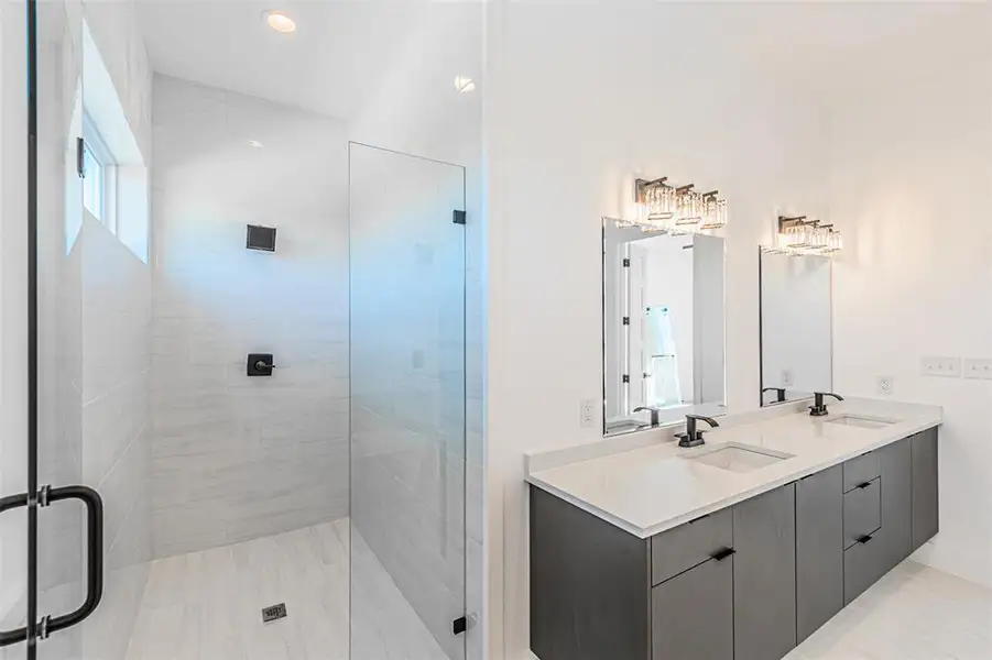 Full bathroom featuring double vanity, a stall shower, and recessed lighting