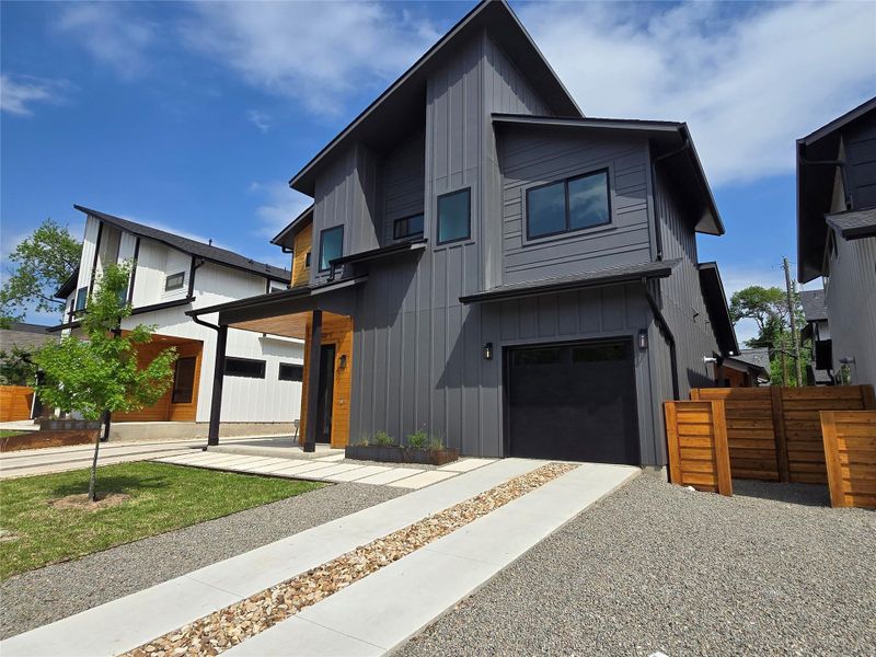 Contemporary house with an attached garage, fence, board and batten siding, and gravel driveway Contemporary house with an attached garage, fence, board and batten siding, and gravel driveway