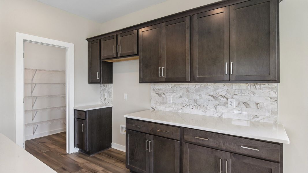 Kitchen with dark cabinetry, quartz countertops, and tile backsplash