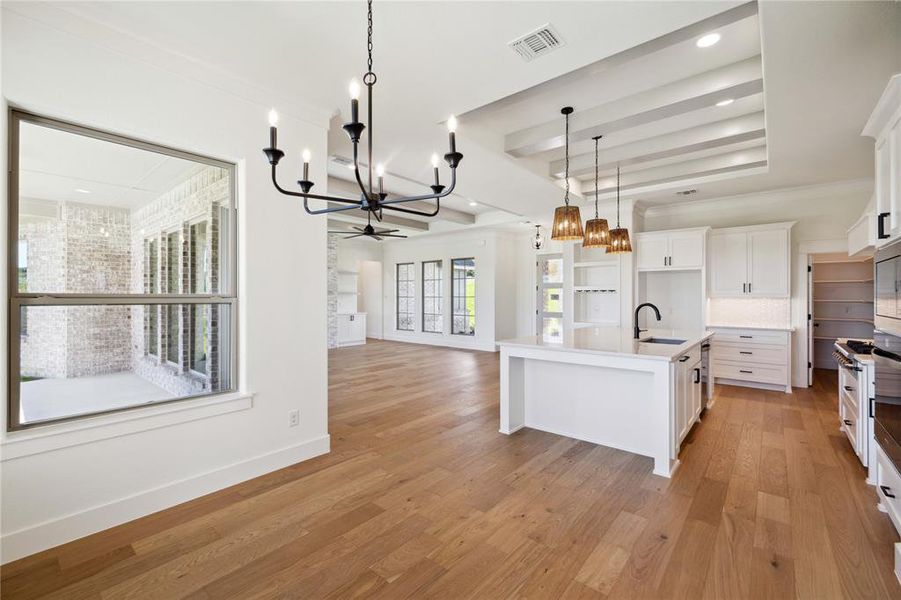 Kitchen with an inviting chandelier, a center island with sink, white cabinets, sink, and light hardwood / wood-style floors