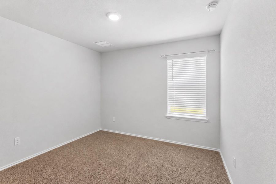 A well-lit bedroom with fresh carpet and natural light pouring in through a window. A well-lit bedroom with fresh carpet and natural light pouring in through a window.