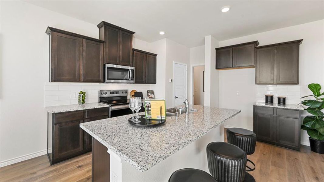 Kitchen featuring backsplash, light stone countertops, a kitchen bar, and recessed lighting
