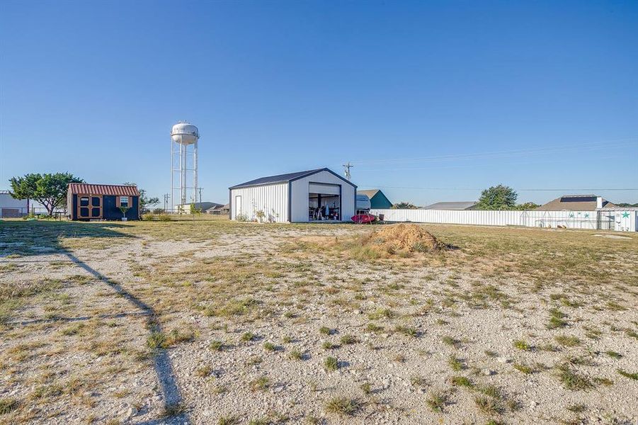 View of yard featuring privacy back fence, storage shed and drive thru garage/workshop. View of yard featuring privacy back fence, storage shed and drive thru garage/workshop.