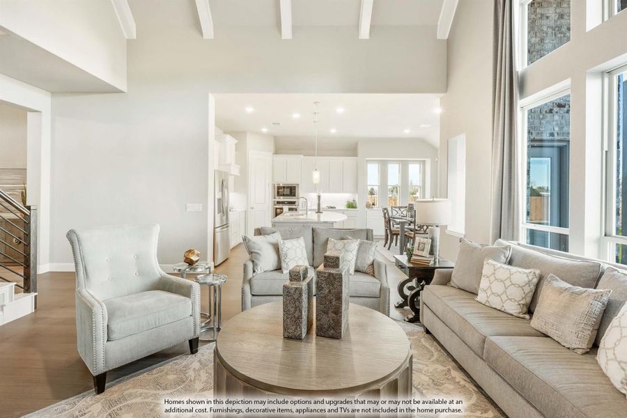 Open-concept living room with high ceilings, gray furniture, and kitchen visible in background