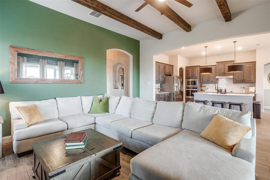 Living room featuring beamed ceiling, ceiling fan, and light hardwood / wood-style floors