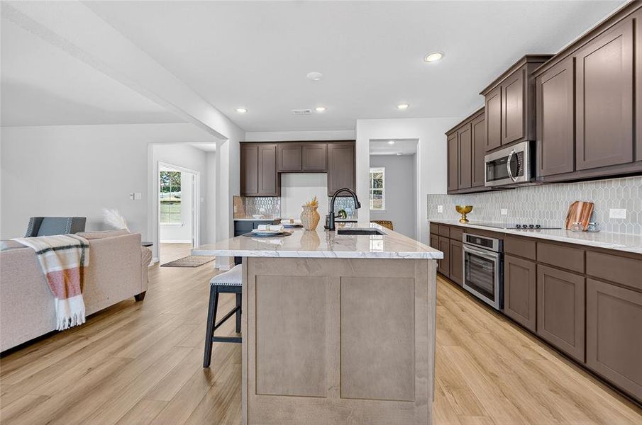 Kitchen with backsplash, a breakfast bar, open floor plan, appliances with stainless steel finishes, and an island with sink Kitchen with backsplash, a breakfast bar, open floor plan, appliances with stainless steel finishes, and an island with sink