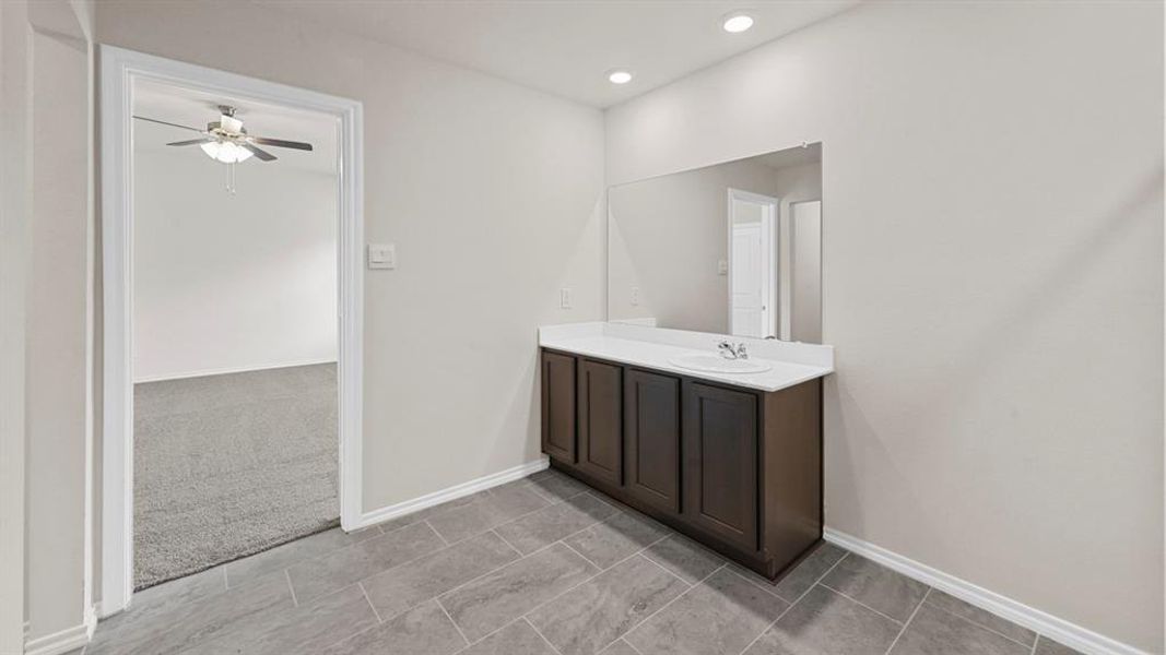Vanity area with a spacious countertop, integrated sink, and dark wood-finish cabinetry Vanity area with a spacious countertop, integrated sink, and dark wood-finish cabinetry