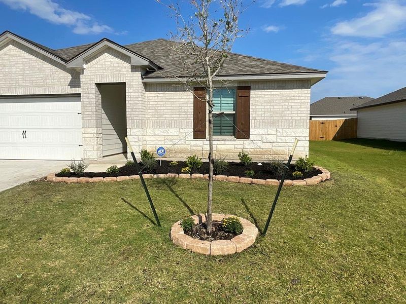 View of front facade featuring a shingled roof, a garage, brick siding, and concrete driveway