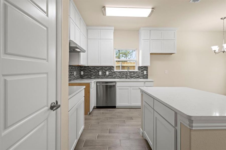 Kitchen with dishwasher, light countertops, a sink, and decorative backsplash