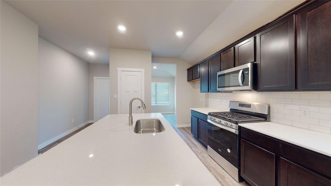 A well-appointed kitchen showcasing a spacious island with sink and modern stainless steel appliances. A well-appointed kitchen showcasing a spacious island with sink and modern stainless steel appliances.