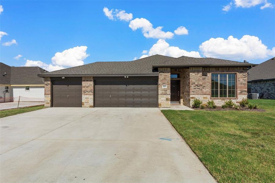 Prairie-style home with a garage, a front lawn, and central air condition unit