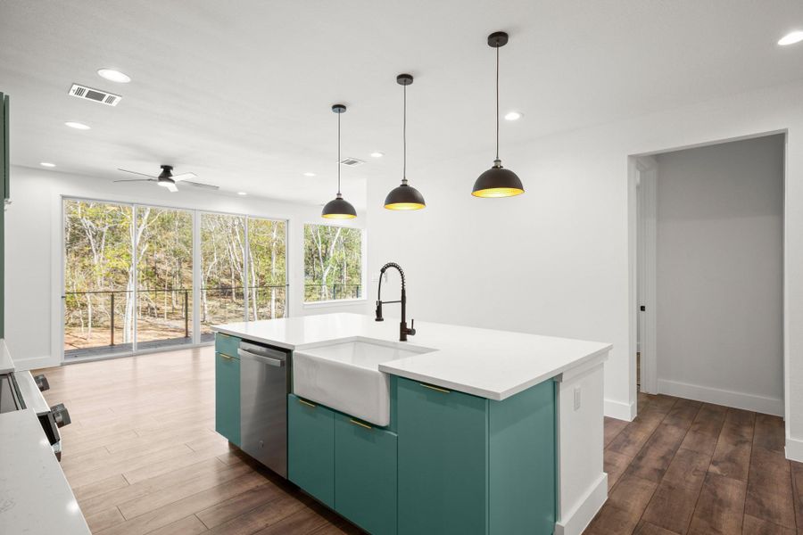 Kitchen featuring green cabinetry, recessed lighting, dark wood finished floors, decorative light fixtures, and an island with sink