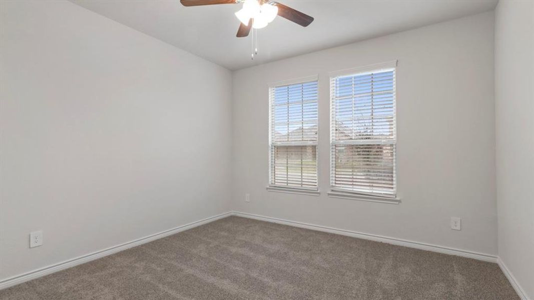 Unfurnished room featuring dark carpet and a ceiling fan