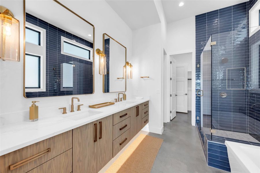 Primary bathroom. Gleaming stone counters pair with a walk-in tiled shower in this modern washroom.