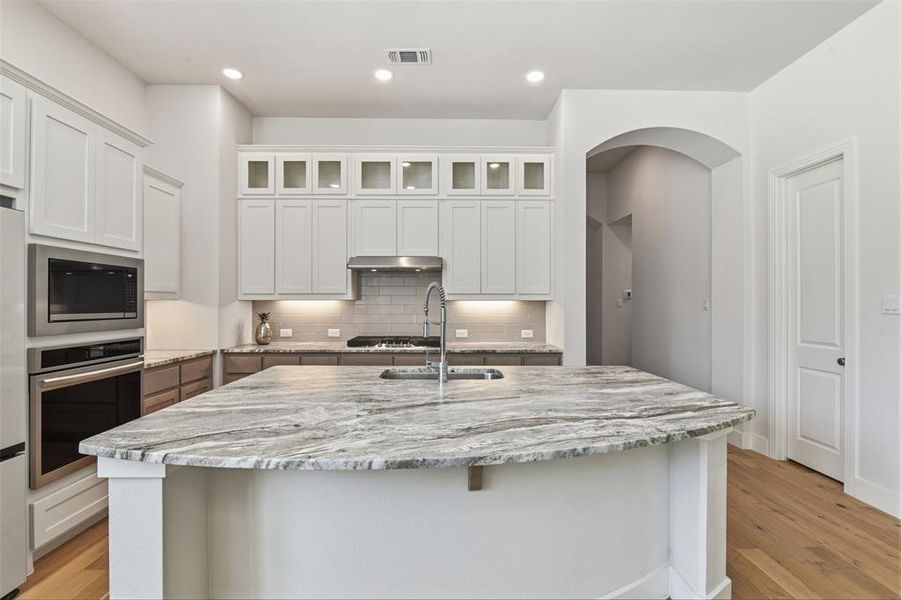 Kitchen island featuring a veined countertop, an undermount sink, and a high-arc faucet Kitchen island featuring a veined countertop, an undermount sink, and a high-arc faucet