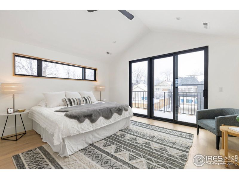 Primary bedroom with vaulted ceilings + deck.