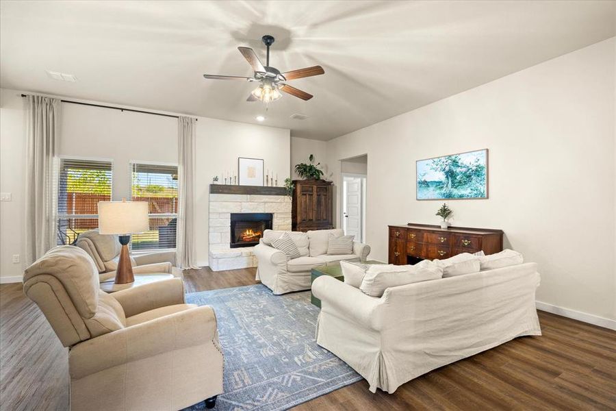 Living room with wood finished floors, a fireplace, and ceiling fan