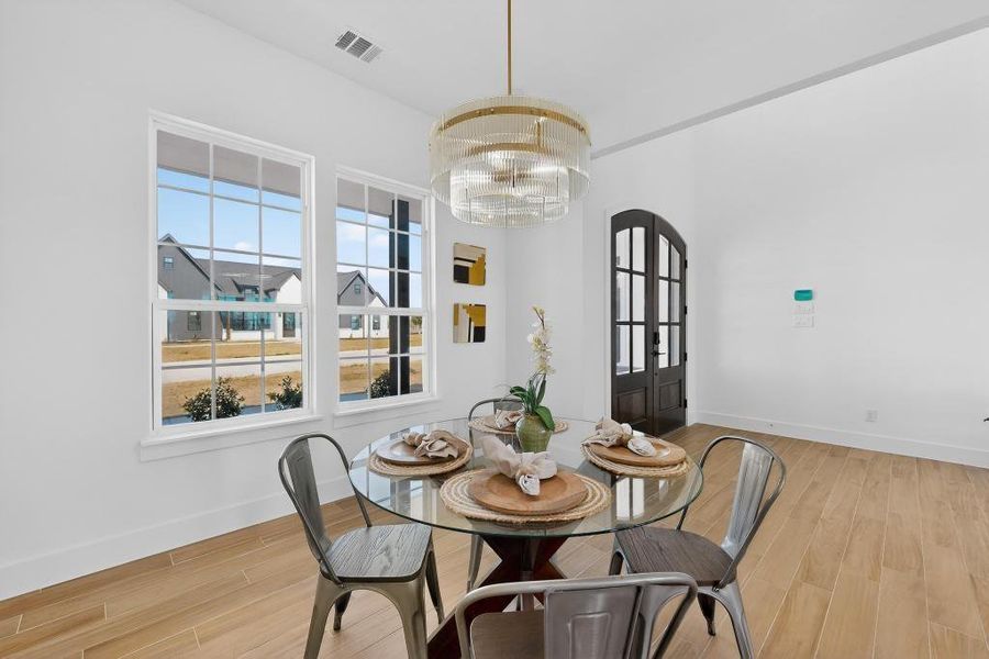 Dining area featuring light wood-style flooring, plenty of natural light, hanging lights, and french doors