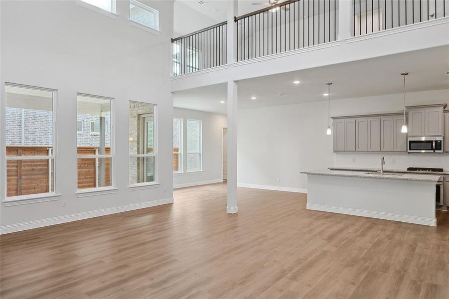Unfurnished living room featuring light wood-style flooring, a high ceiling, recessed lighting, and a ceiling fan Unfurnished living room featuring light wood-style flooring, a high ceiling, recessed lighting, and a ceiling fan