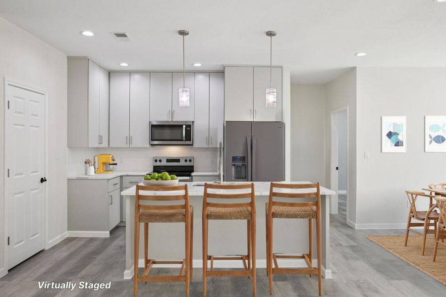 Virtually Staged Kitchen with stainless steel appliances, a kitchen bar, an island with sink, decorative light fixtures, and  light wood-type laminate flooring