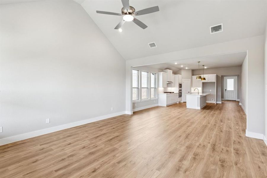 Unfurnished living room with light wood-style floors, high vaulted ceiling, ceiling fan, and recessed lighting