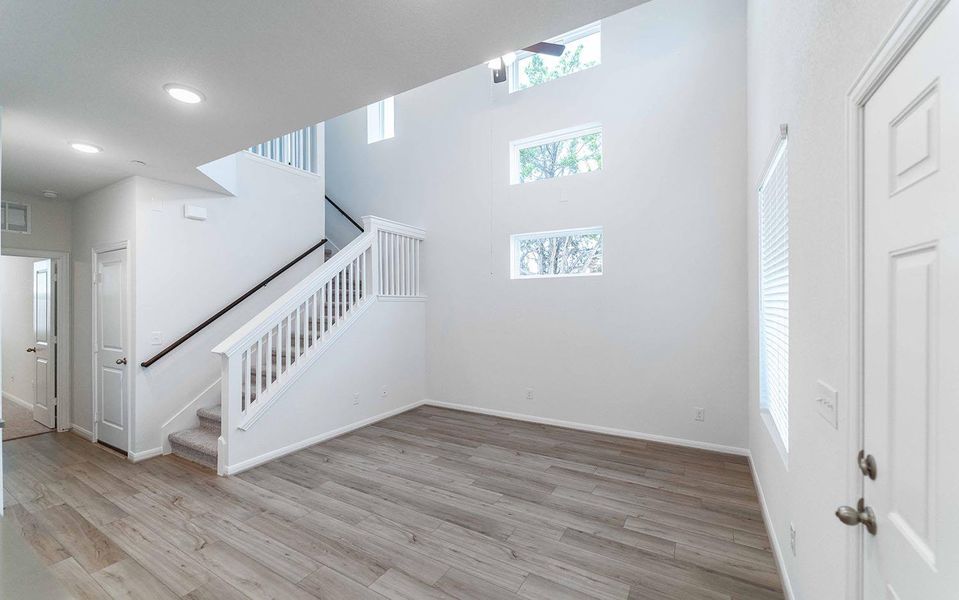 Unfurnished living room with a high ceiling, light wood-type flooring, and plenty of natural light
