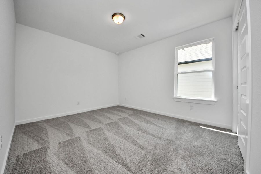 Secondary bedroom features plush carpeting, large windows that let in plenty of natural light, bright paint, and spacious closets. Sample photo of completed home with similar floor plan. Actual colors and selections may vary.