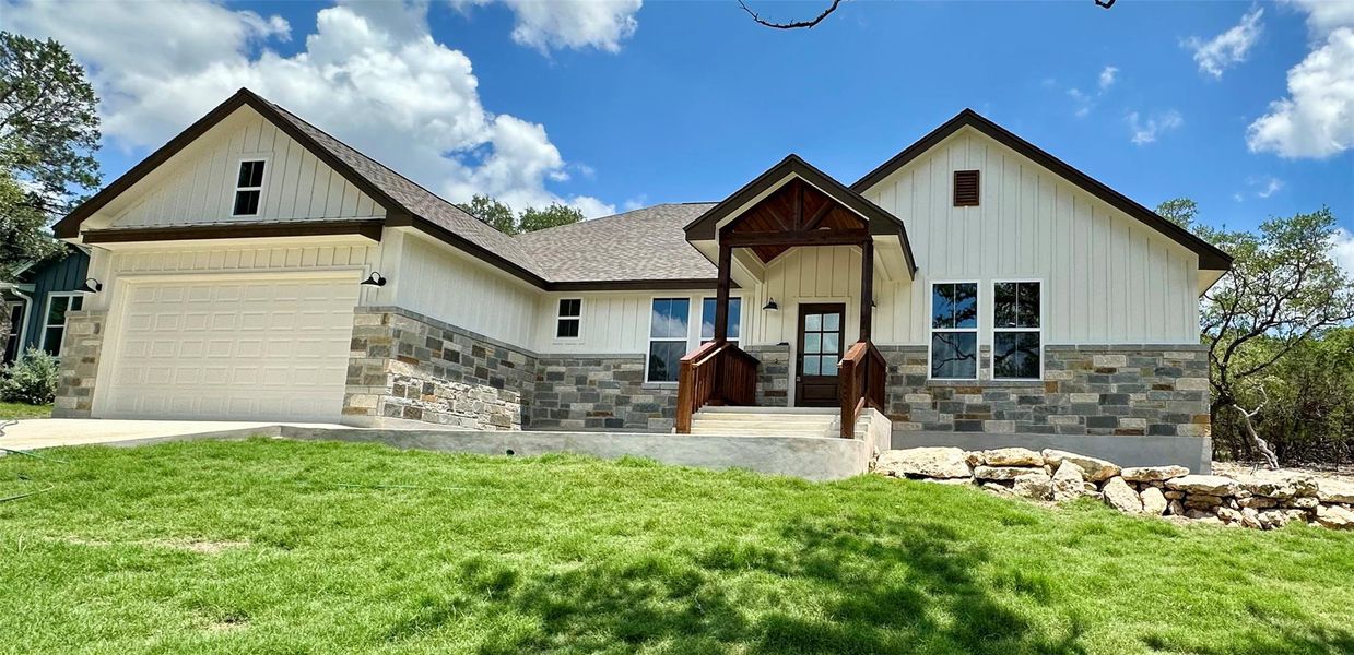 Modern inspired farmhouse with stone siding, a front yard, and a garage Modern inspired farmhouse with stone siding, a front yard, and a garage