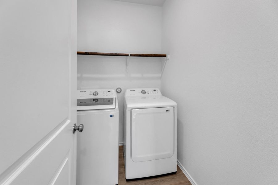 Clothes washing area featuring baseboards, laundry area, washing machine and clothes dryer, and wood finished floors