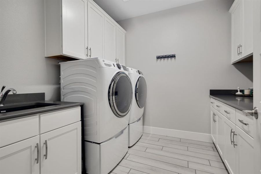 Large laundry room with plenty of cabinets and a sink.