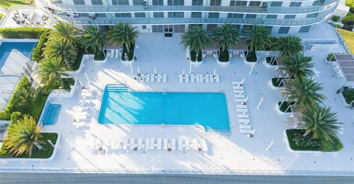 Swimming pool with an integrated spa, paved sun deck, and mature palm landscaping