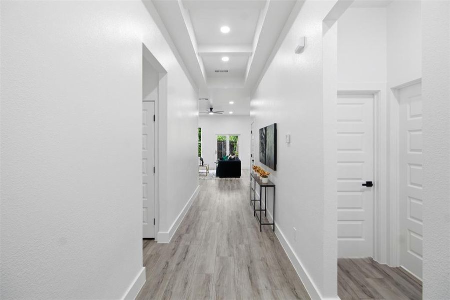Hallway featuring recessed lighting, wood-finish flooring, white paneled doors, and contemporary baseboards