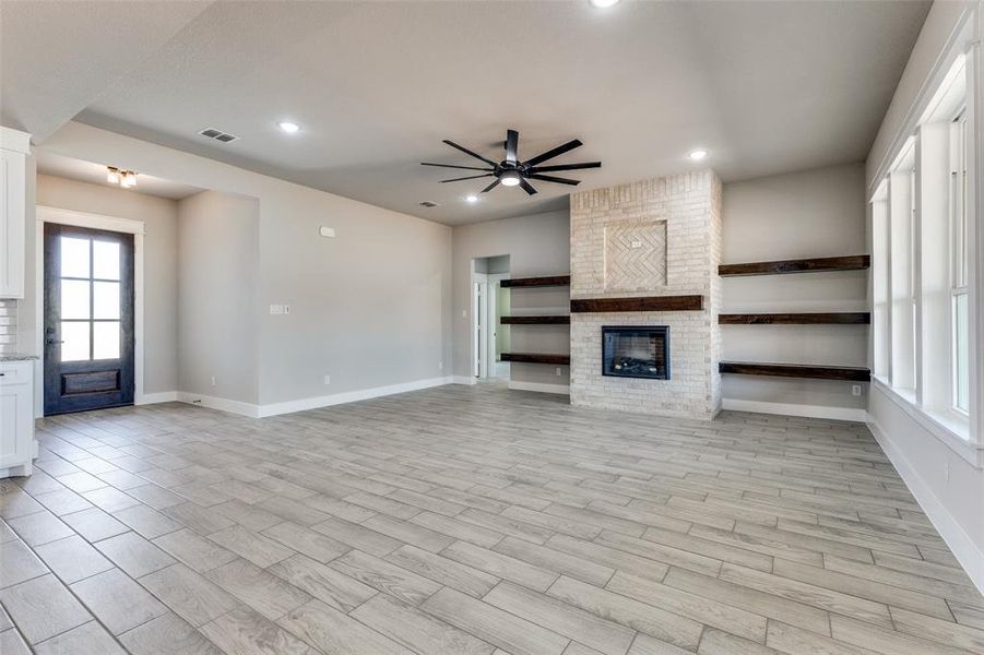 Unfurnished living room with light hardwood / wood-style flooring, ceiling fan, and a fireplace