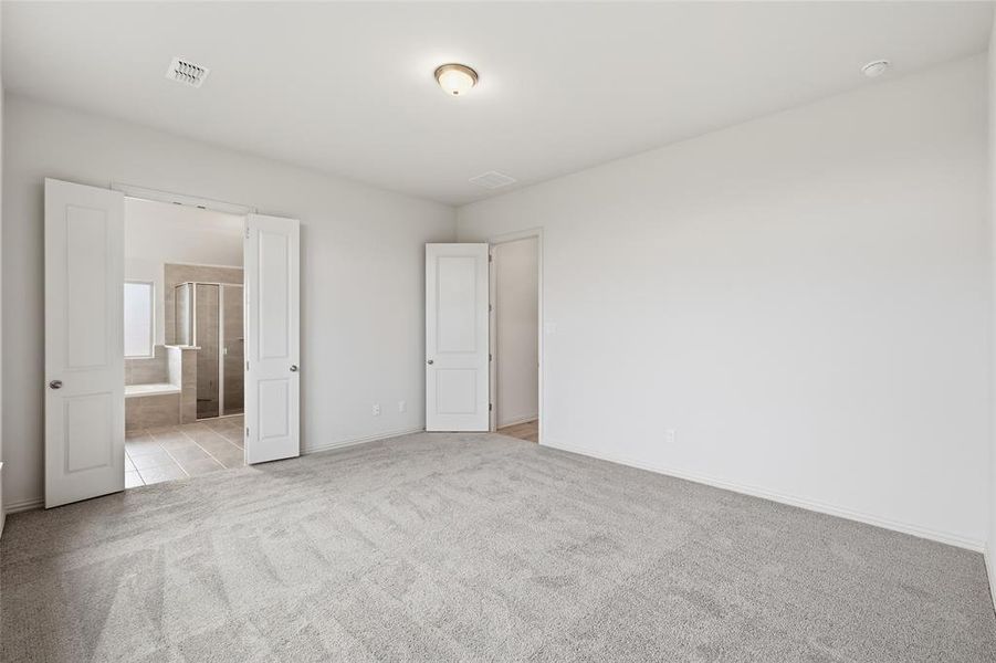 Spacious room featuring light-toned carpet flooring and white walls Spacious room featuring light-toned carpet flooring and white walls