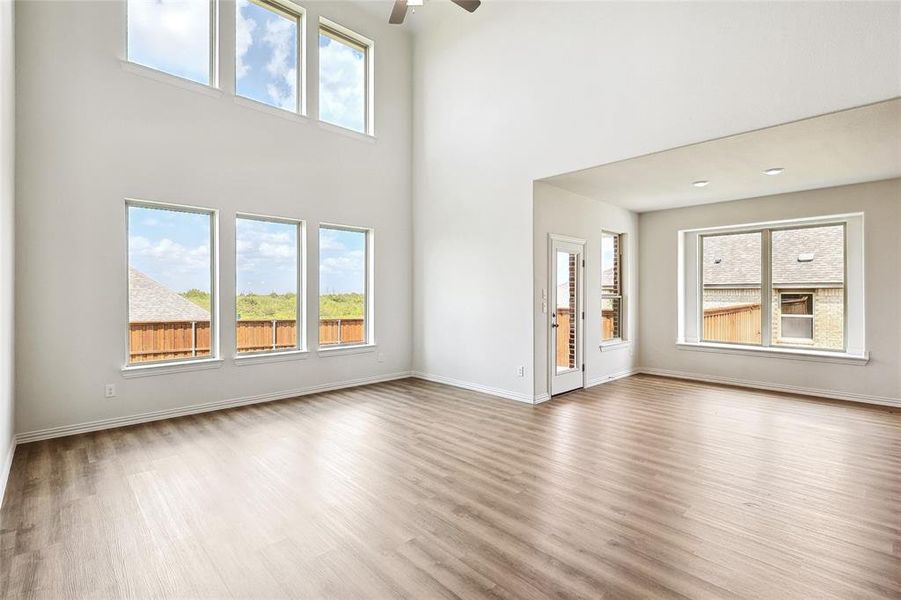 Unfurnished living room with light hardwood / wood-style floors, a towering ceiling, and ceiling fan