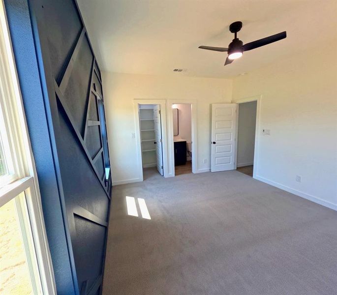 Unfurnished bedroom featuring carpet floors, ensuite bathroom, a ceiling fan, and a spacious closet Unfurnished bedroom featuring carpet floors, ensuite bathroom, a ceiling fan, and a spacious closet