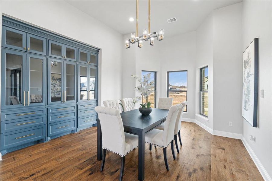 Dining area with a towering ceiling, hardwood / wood-style floors, and a notable chandelier