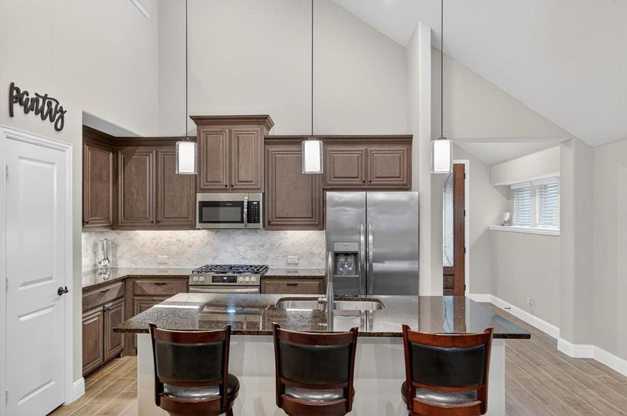 Kitchen featuring dark wood cabinetry, granite countertops, and stainless steel appliances Kitchen featuring dark wood cabinetry, granite countertops, and stainless steel appliances