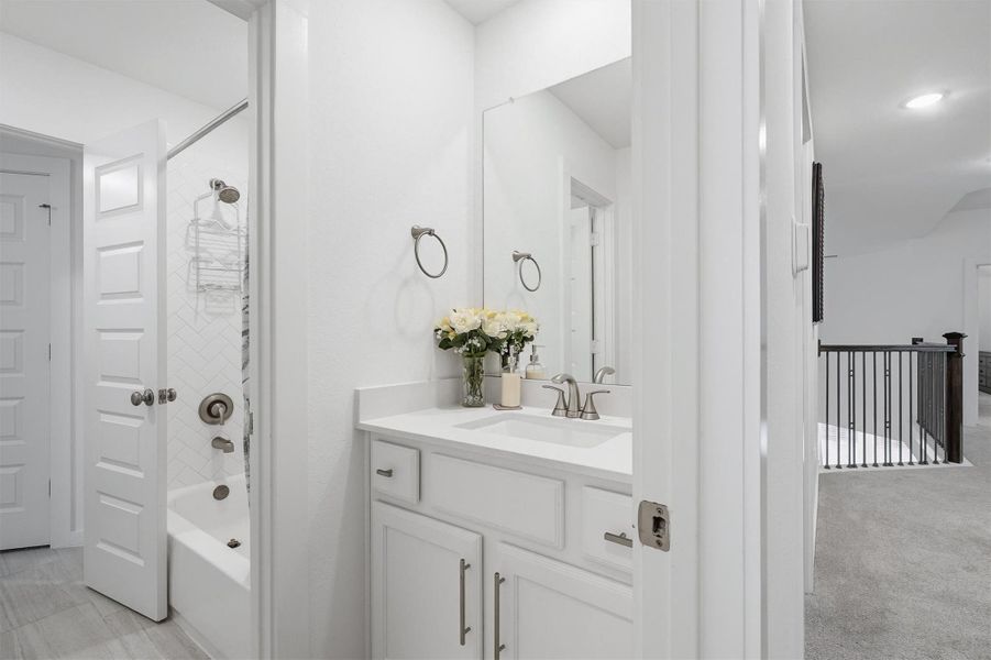 This thoughtfully designed split bathroom features a shower/tub combo and private toilet area in one section, with separate sink vanities on each side, offering convenience, privacy, and efficient use of space.