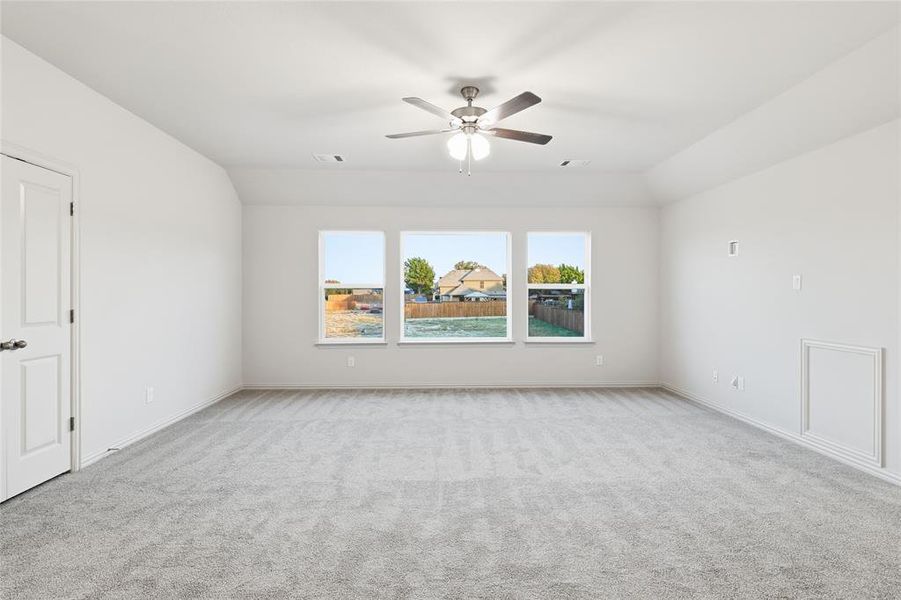Empty room with light carpet, lofted ceiling, and a ceiling fan