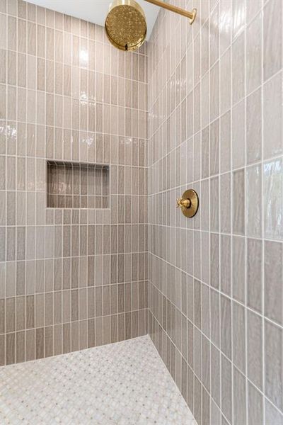 Shower featuring vertical subway tile walls in a neutral tone, complemented by a mosaic tile floor Shower featuring vertical subway tile walls in a neutral tone, complemented by a mosaic tile floor