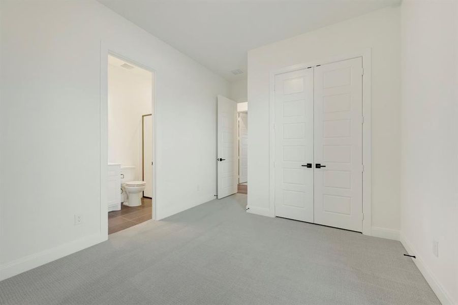 Unfurnished bedroom with light carpet, a closet, and ensuite bathroom Unfurnished bedroom with light carpet, a closet, and ensuite bathroom