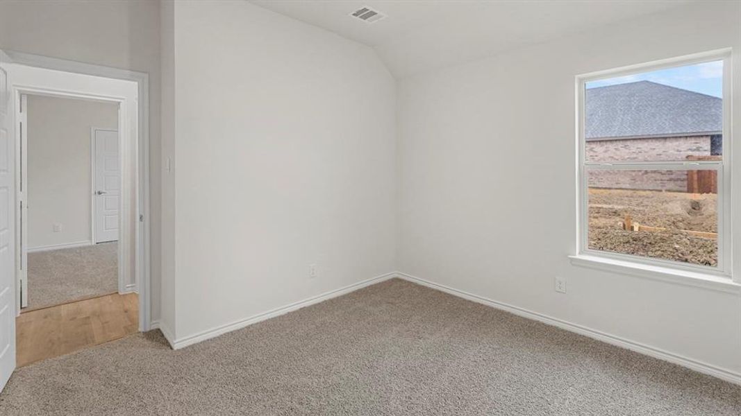 Carpeted empty room featuring vaulted ceiling and baseboards Carpeted empty room featuring vaulted ceiling and baseboards