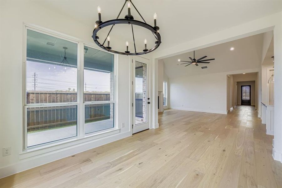 Unfurnished dining area featuring a ceiling fan, a chandelier, light wood finished floors, vaulted ceiling, and recessed lighting Unfurnished dining area featuring a ceiling fan, a chandelier, light wood finished floors, vaulted ceiling, and recessed lighting