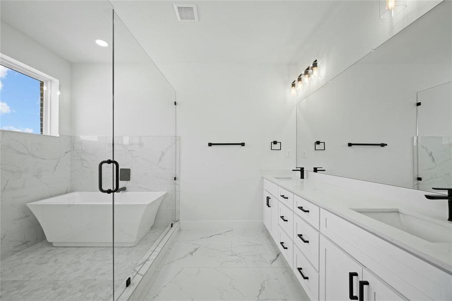 Bathroom with marble tiled flooring, double vanity, a freestanding tub, and recessed lighting